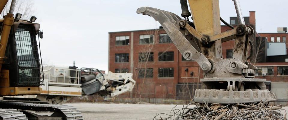Pelle mécanique à pince de tri en démolition d'un bâtiment industriel