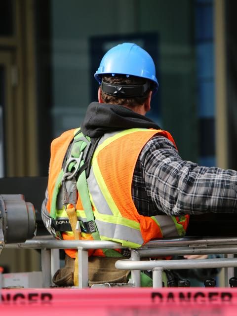 Compagnon de dos en gilet haute visibilité, au travail sur un chantier balisé