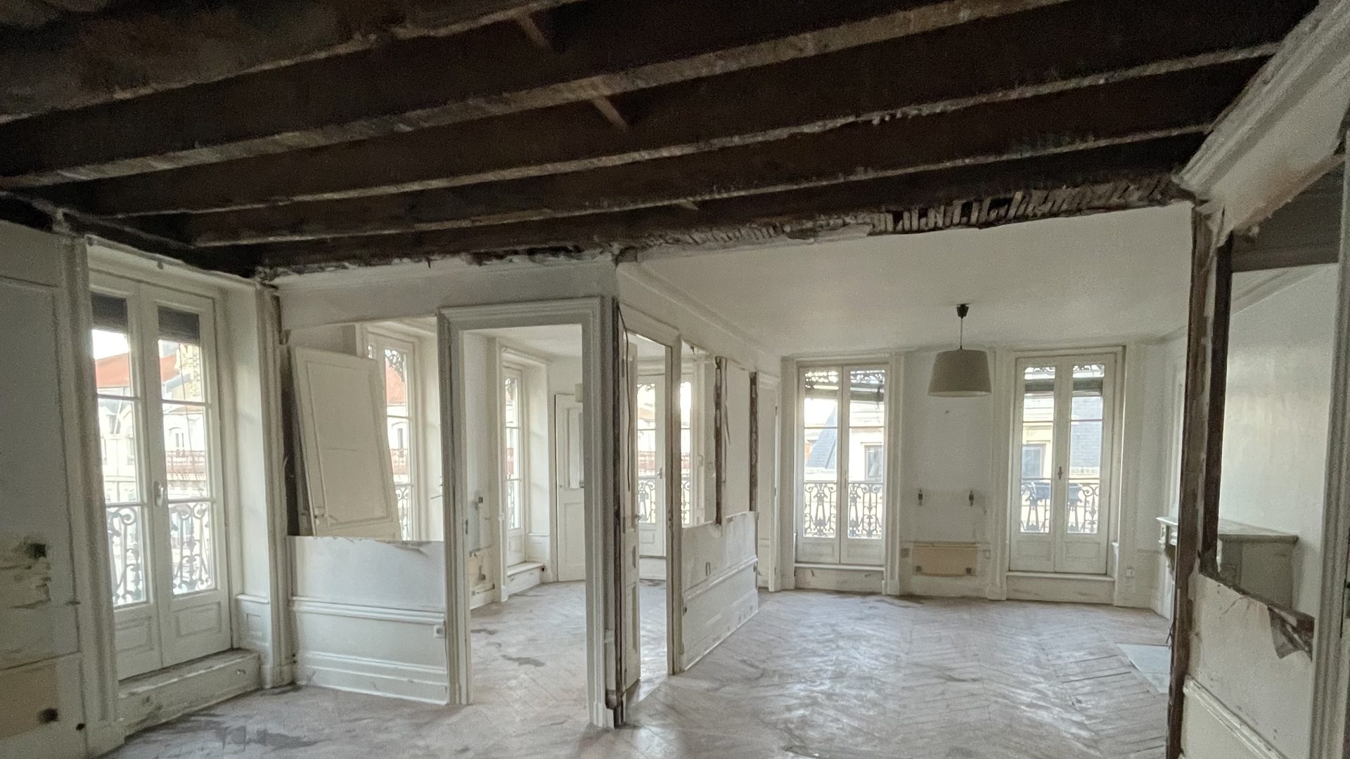 Curage d'un appartement ancien à Lyon : parquet protégé, poutres apparentes après dépose des plafonds