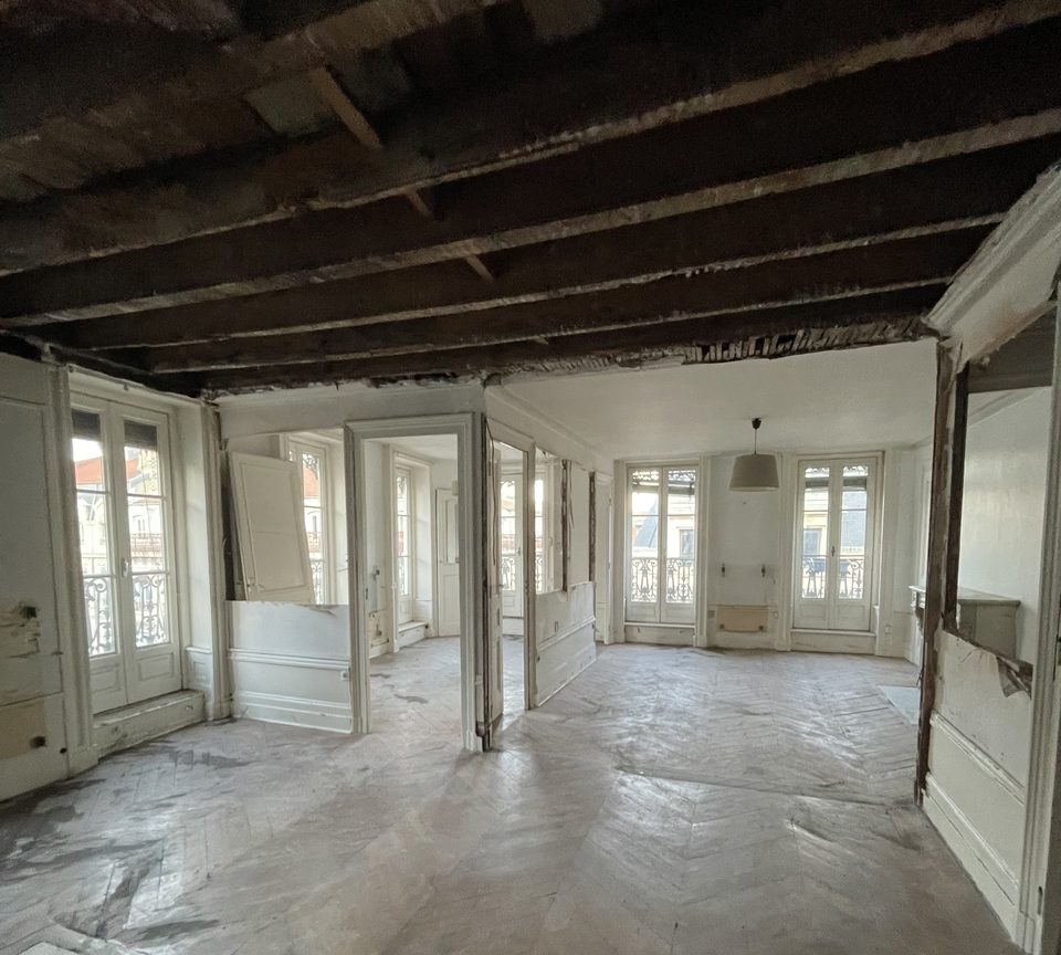Curage d'un appartement ancien à Lyon : parquet protégé, poutres apparentes après dépose des plafonds