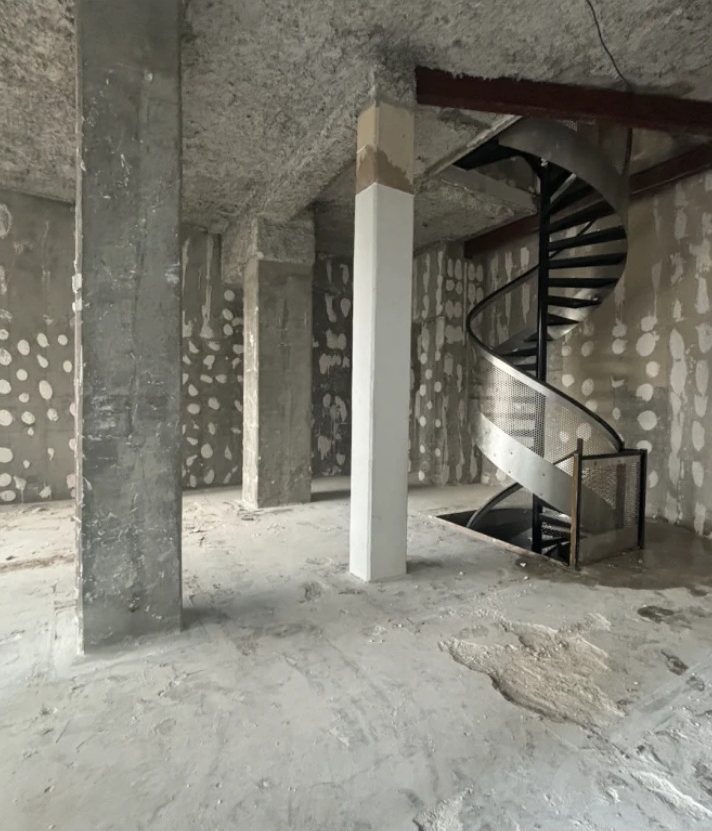 Démolition intérieure à Lyon 2e : poteaux et dalle mis à nu autour de l'escalier conservé