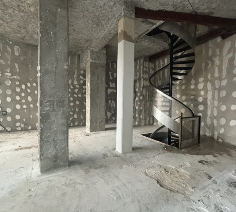 Démolition intérieure à Lyon 2e : poteaux et dalle mis à nu autour de l'escalier conservé